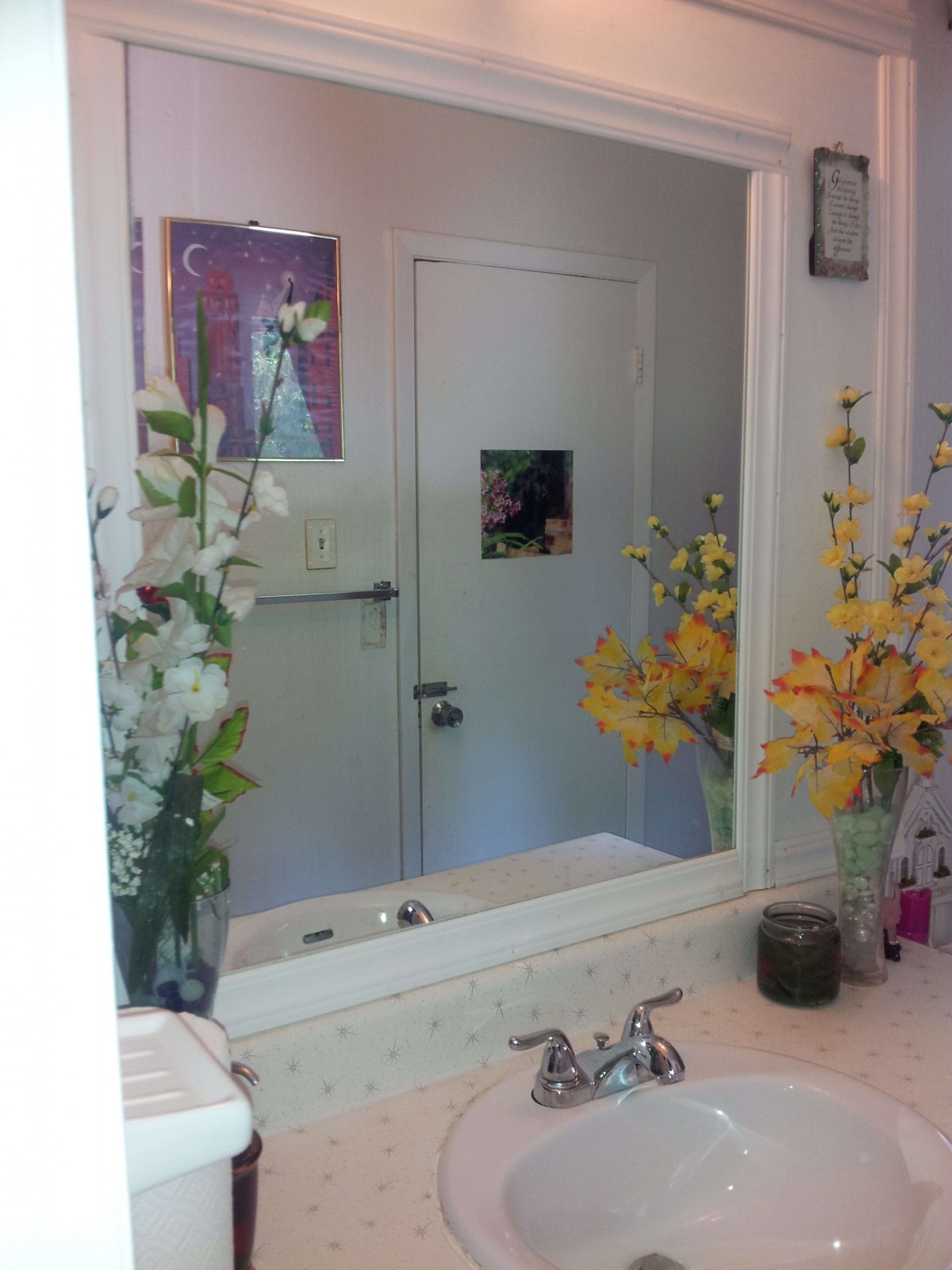 A bathroom with a mirror reflecting floral decorations and a closed door.