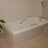 A modern bathtub in a tiled bathroom.