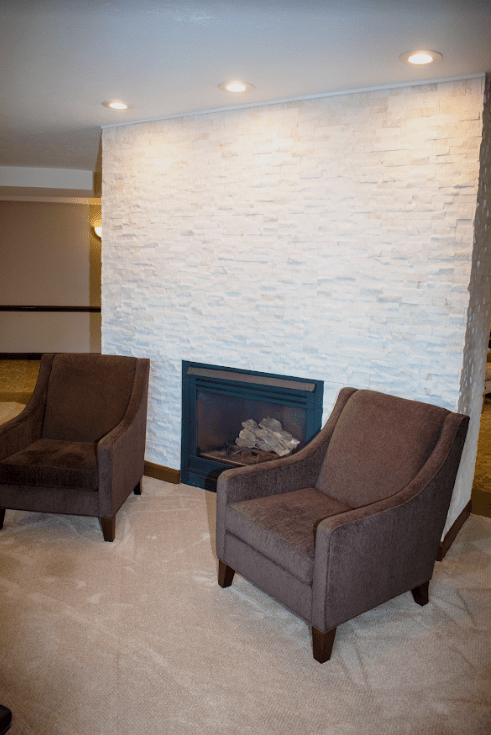 A modern living room with two brown chairs facing a stone fireplace.