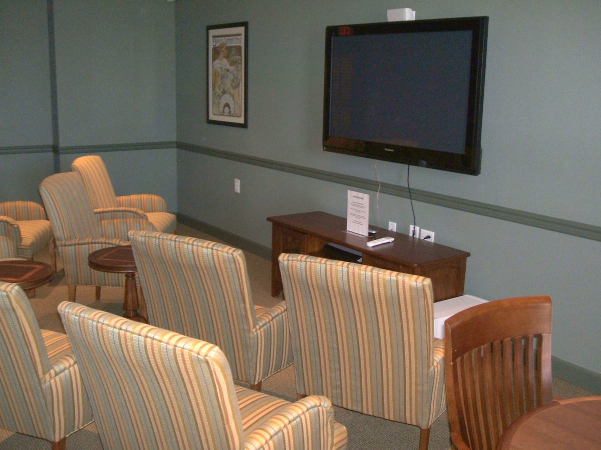 A cozy waiting room with several chairs facing a large wall-mounted television.