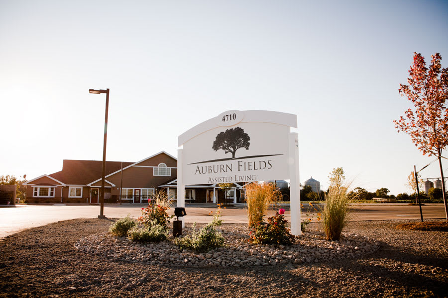 A building with a prominent sign in front, surrounded by landscaping under a clear sky.