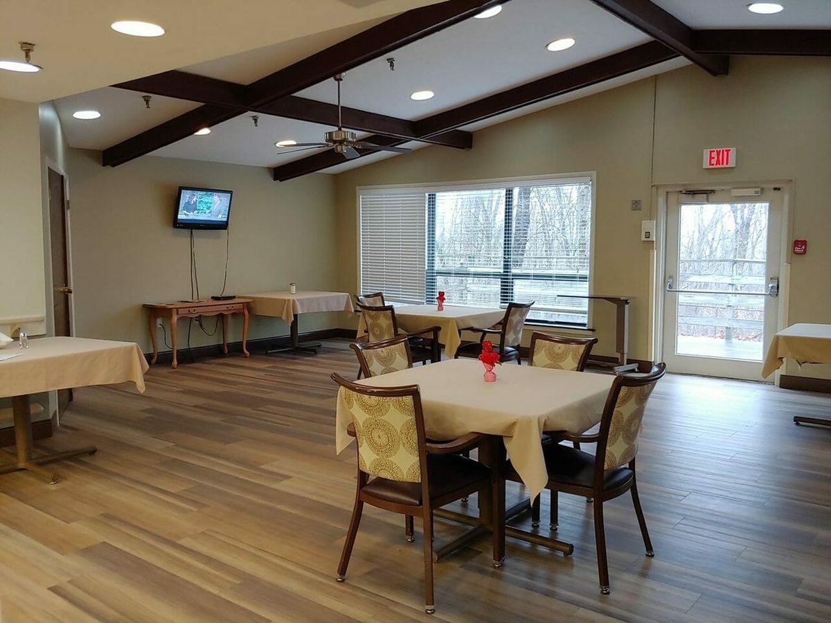 A cozy dining area with tables, chairs, and a television.