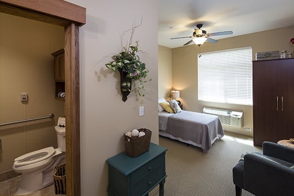 A cozy bedroom with a bed, ceiling fan, and decorative elements.