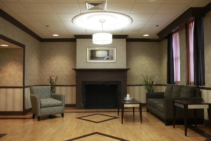 A cozy living room featuring a modern fireplace, two sofas, and a central coffee table under a contemporary ceiling light.