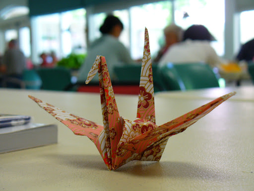 An intricately folded origami crane made from patterned paper.