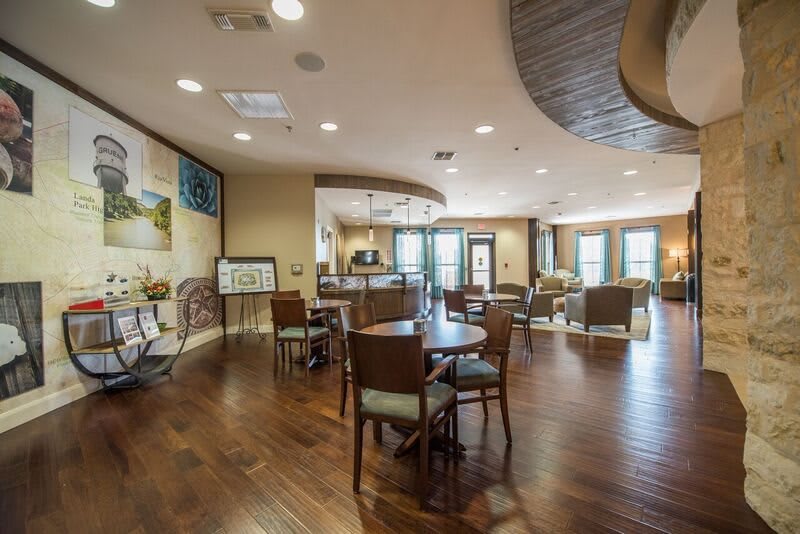 A spacious and well-lit interior room with wooden floors, furnished with tables and chairs.