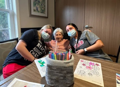 A joyful moment shared between caregivers and a senior during a coloring activity.