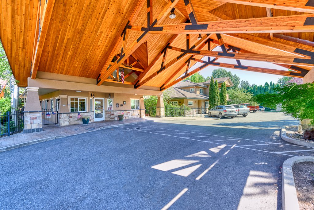 A spacious carport with a wooden roof structure on a sunny day.