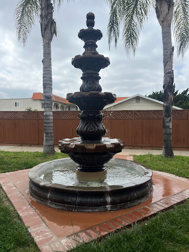 A beautifully designed fountain surrounded by palm trees, adding a serene touch to the outdoor landscape.