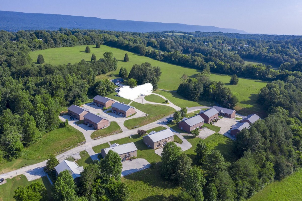 Aerial view of a campus surrounded by greenery and open fields.