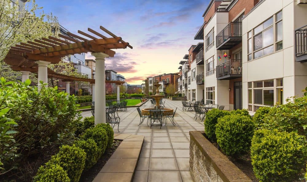 A beautifully landscaped apartment complex with outdoor seating and balconies at sunset.