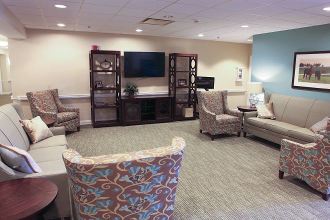 A cozy living room with armchairs, a sofa, and a large television on a shelving unit.