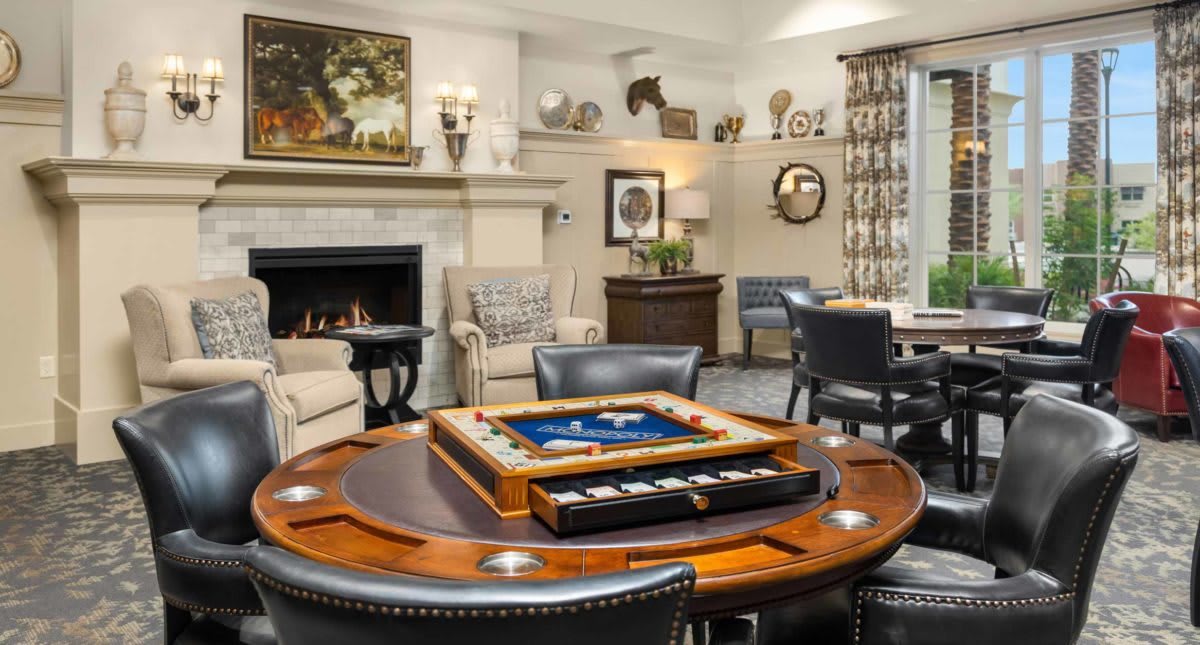 A cozy living room featuring a fireplace and a game table surrounded by comfortable seating.