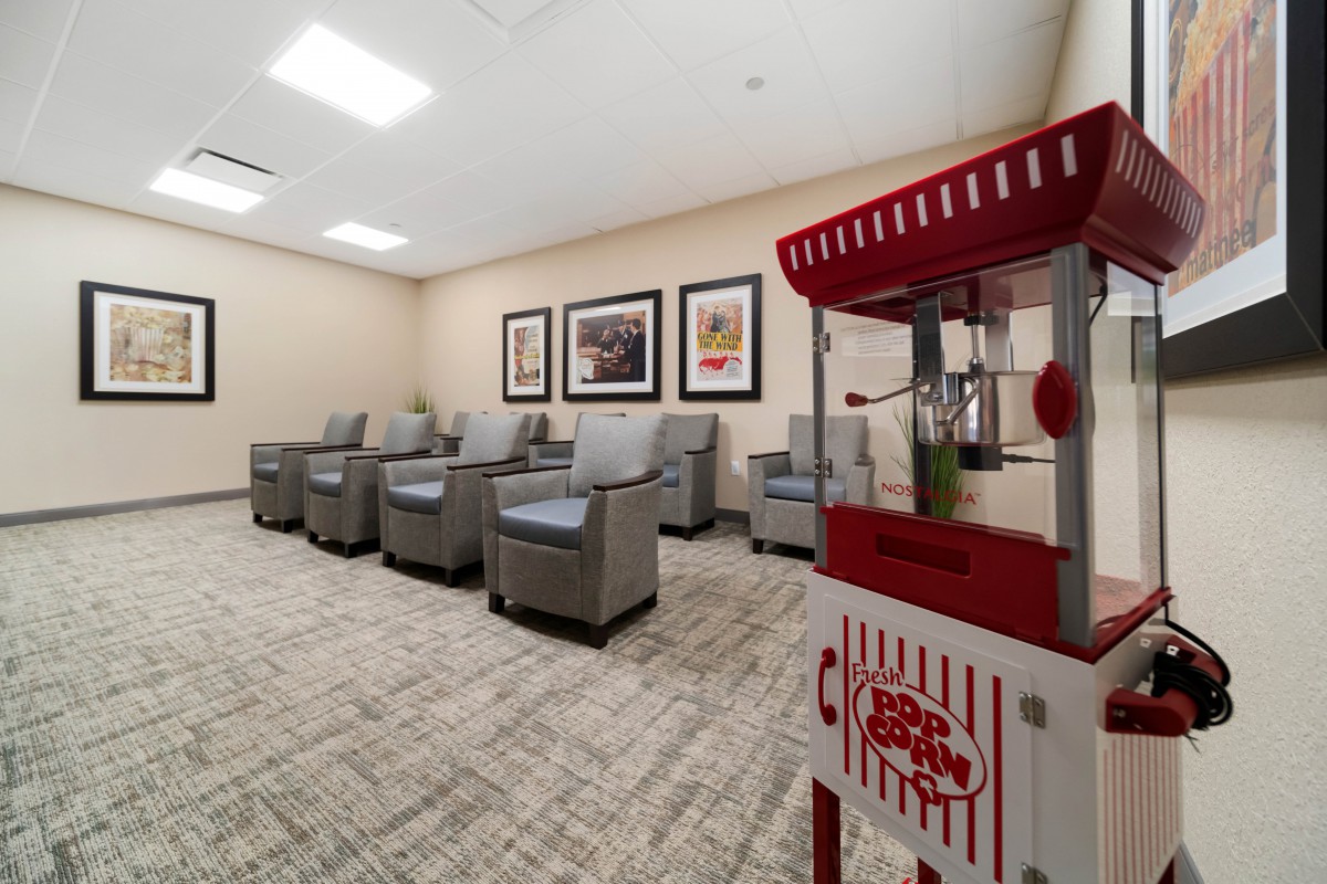 A comfortable waiting room with a row of armchairs, decorative artwork on the walls, and a popcorn machine in the corner.
