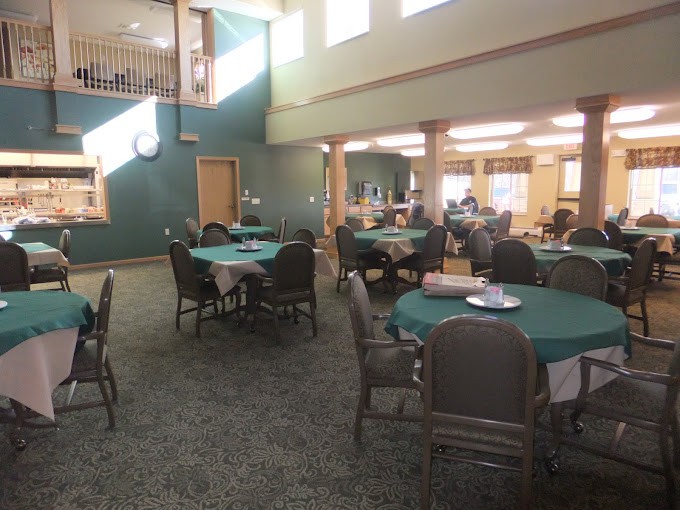 A spacious dining area with multiple tables and chairs, lit by natural light.