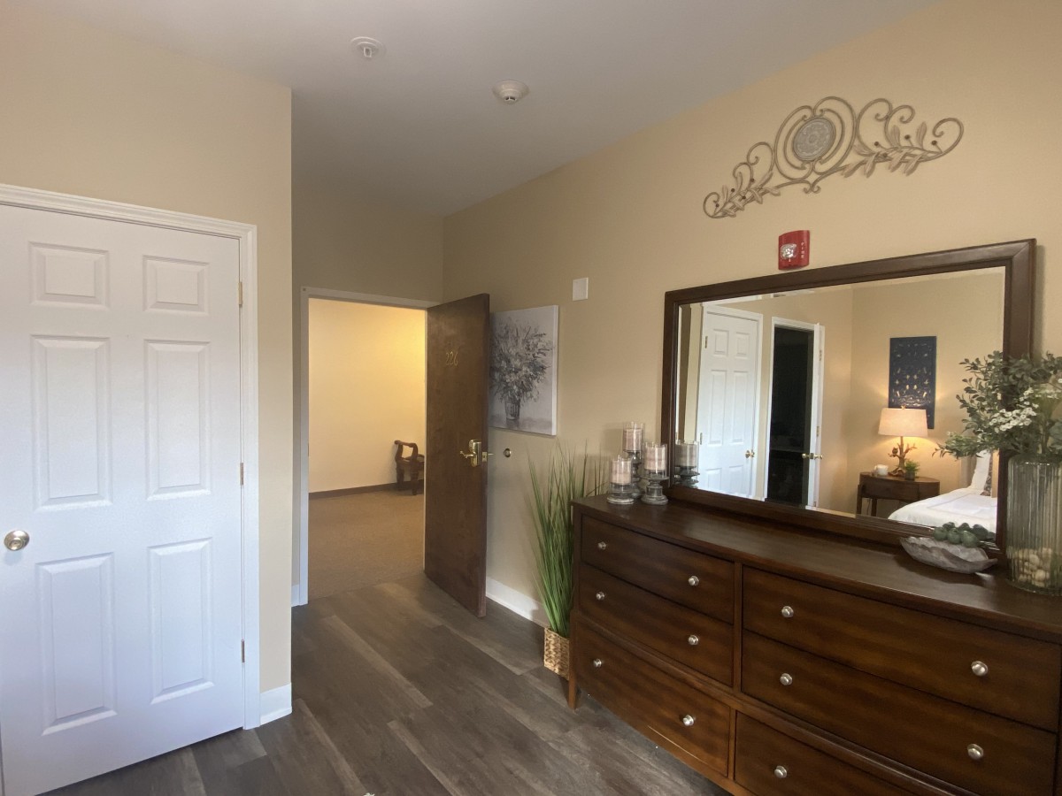 A cozy bedroom with a large dresser and mirror, complemented by warm lighting and stylish decor.