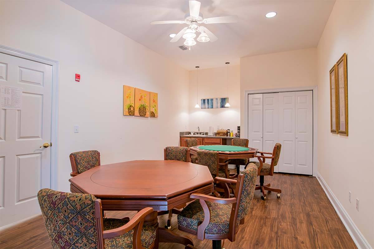 A cozy game room with multiple tables and chairs, featuring wood flooring and decorative wall art.