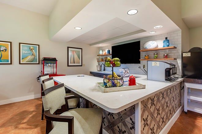 A modern kitchen interior with a bar counter and seating, featuring stylish decor and lighting.