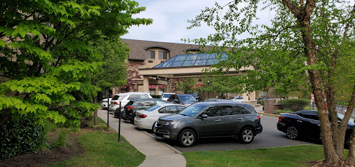 A view of a parking lot in front of a building with glass architecture.
