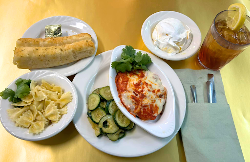 A delicious dinner plate featuring pasta, sauted cucumbers, a cheese-topped dish, and a side of dessert.