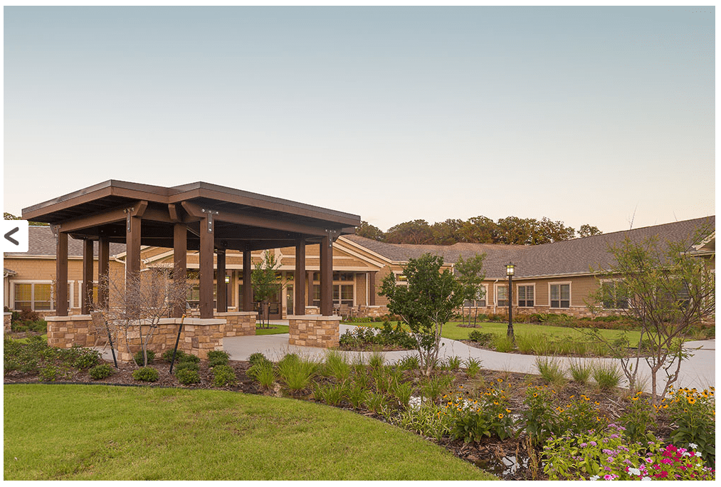 A modern building surrounded by a well-maintained garden and lush green lawn.