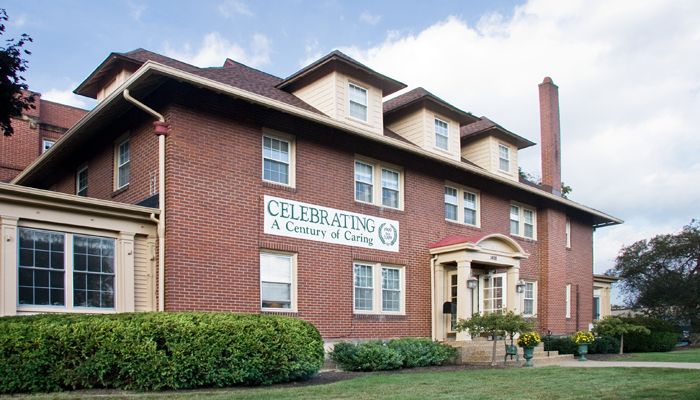 A historic brick building with a sign celebrating a century of service.