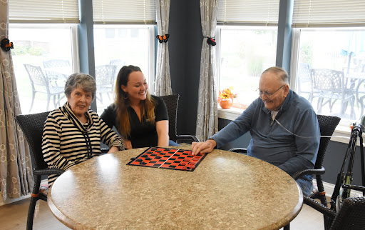 A joyful gathering of three individuals enjoying a game together at a cozy indoor setting.