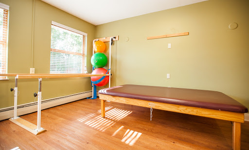 A bright and inviting therapy room equipped with exercise balls and a treatment table.