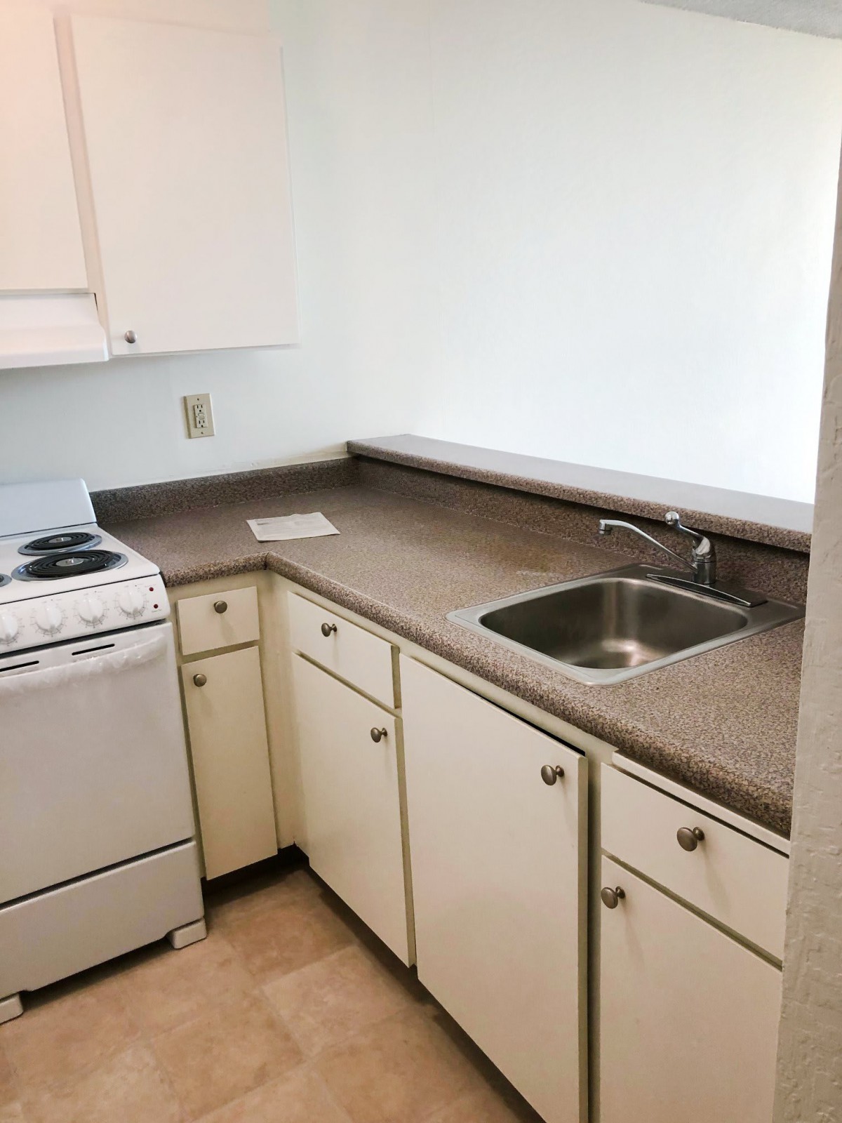 A compact kitchen with a stove, sink, and cabinets.