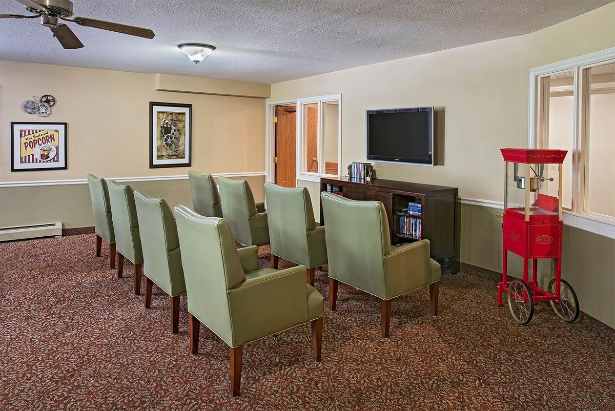 A cozy indoor theater room with comfortable chairs facing a large television, featuring a popcorn machine on the side.