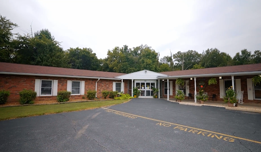A view of a modest brick motel with a welcoming entrance and landscaped surroundings.