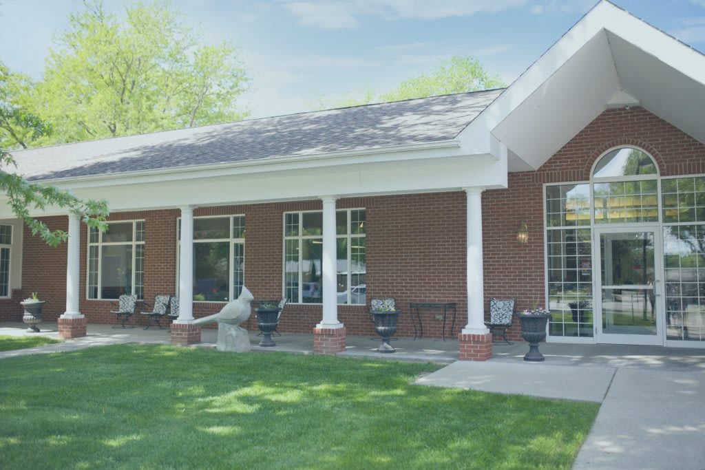 A brick building with white columns and a green lawn under a clear sky.
