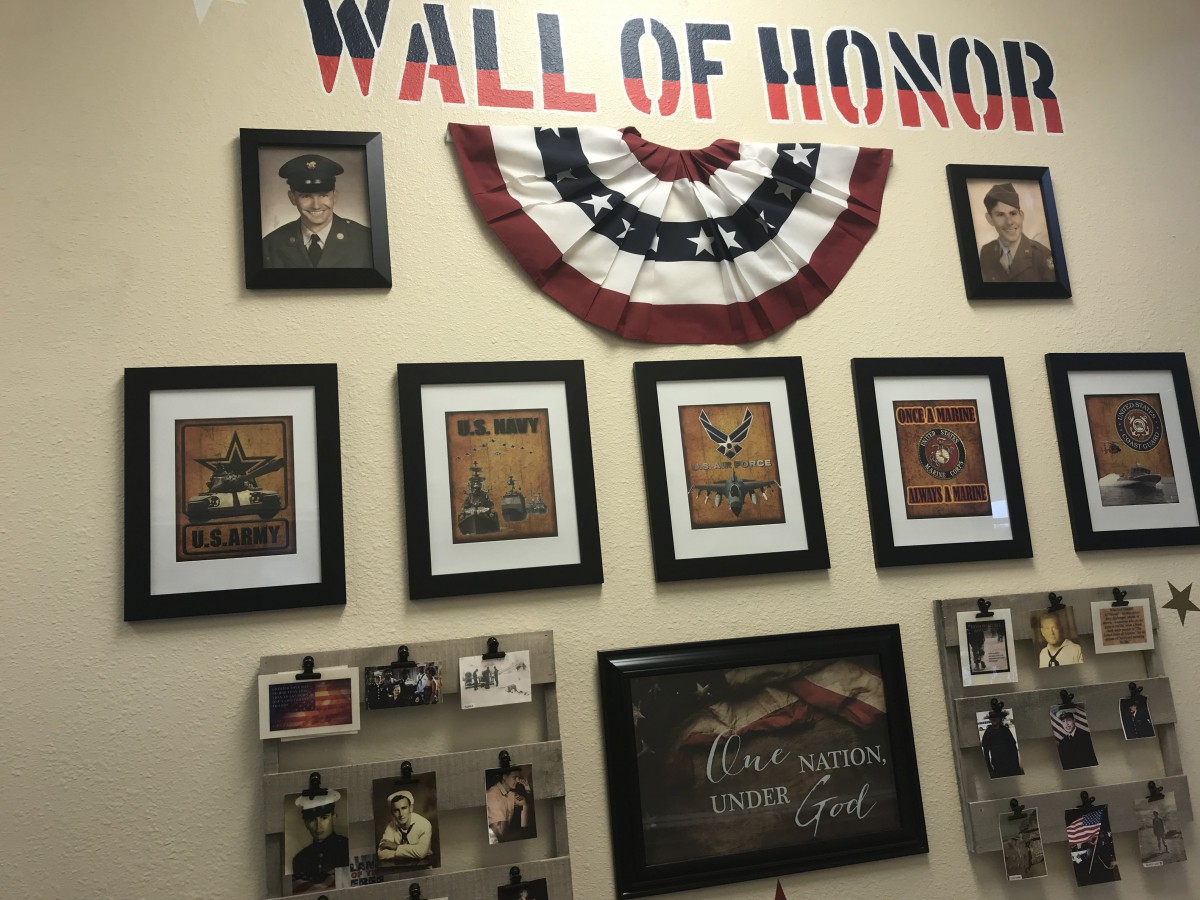 A Wall of Honor displaying framed photographs and memorabilia in tribute to veterans, adorned with patriotic decorations.