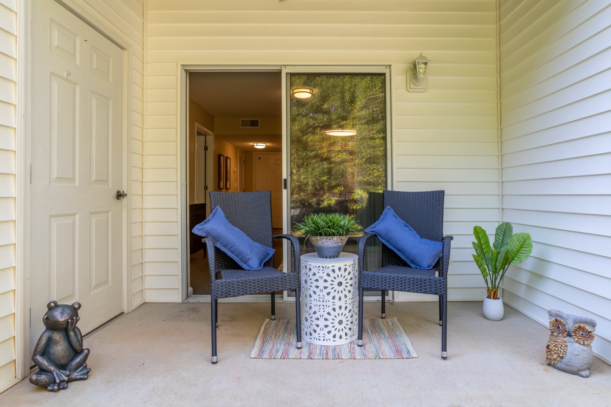 Cozy patio setup with chairs and a small table adorned with a potted plant.