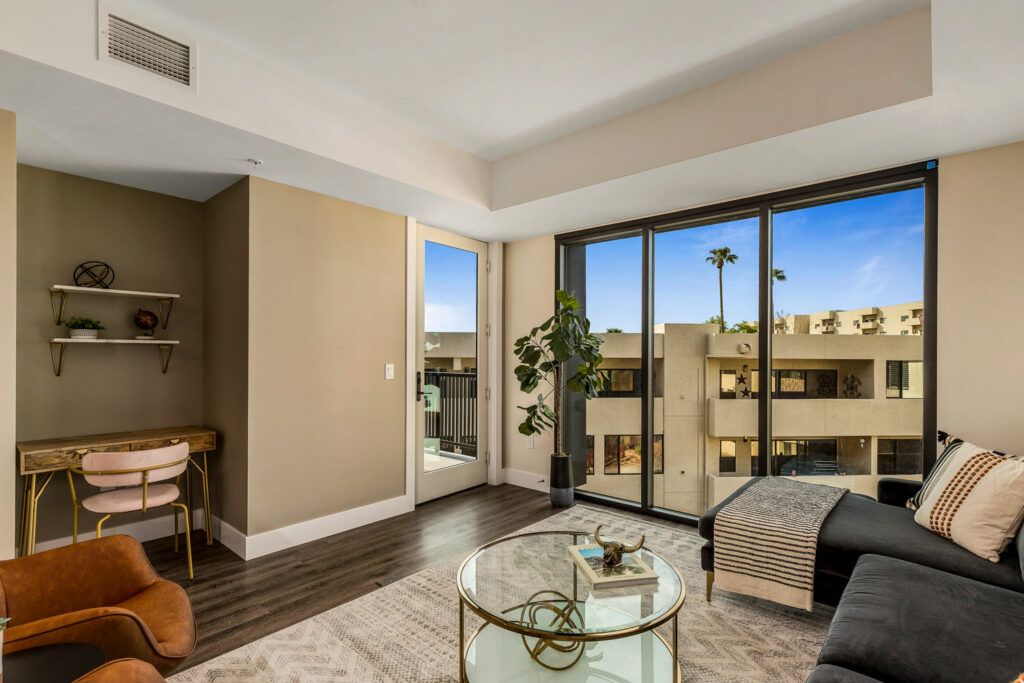 A modern living room with glass doors leading to a balcony, filled with natural light.