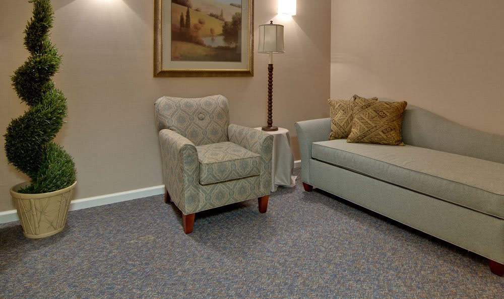 A cozy living room with an armchair, sofa, and lamp, showcasing a warm and inviting interior.