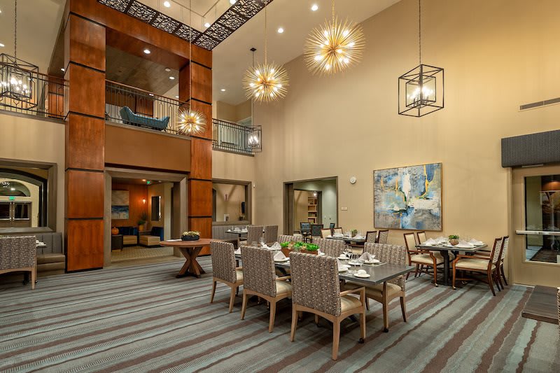 A modern dining room with high ceilings, elegant chandeliers, and contemporary artwork.