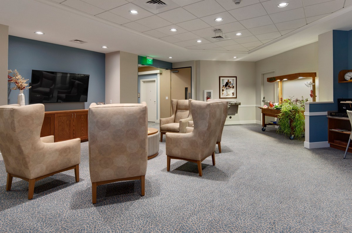 A comfortable lounge area with upholstered chairs, a television, and decorative artwork on the wall.