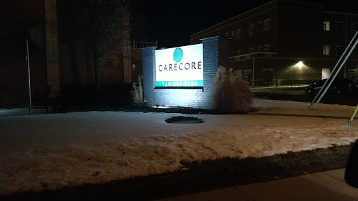 A illuminated business sign at night, partially surrounded by snow.