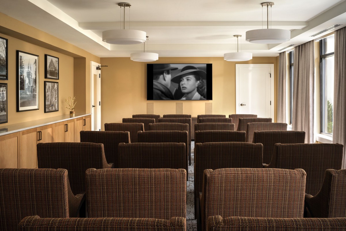A small movie theater with rows of chairs and a black and white film playing on the screen.
