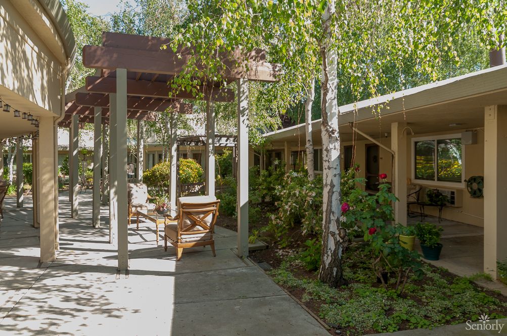 A peaceful garden pathway with trees and outdoor seating.