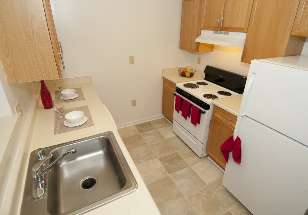 Compact apartment kitchen with essential appliances and wooden cabinets.