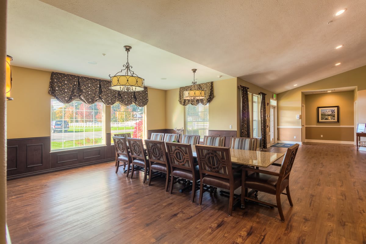 Spacious dining area with a long table, elegant chandeliers, and large windows.