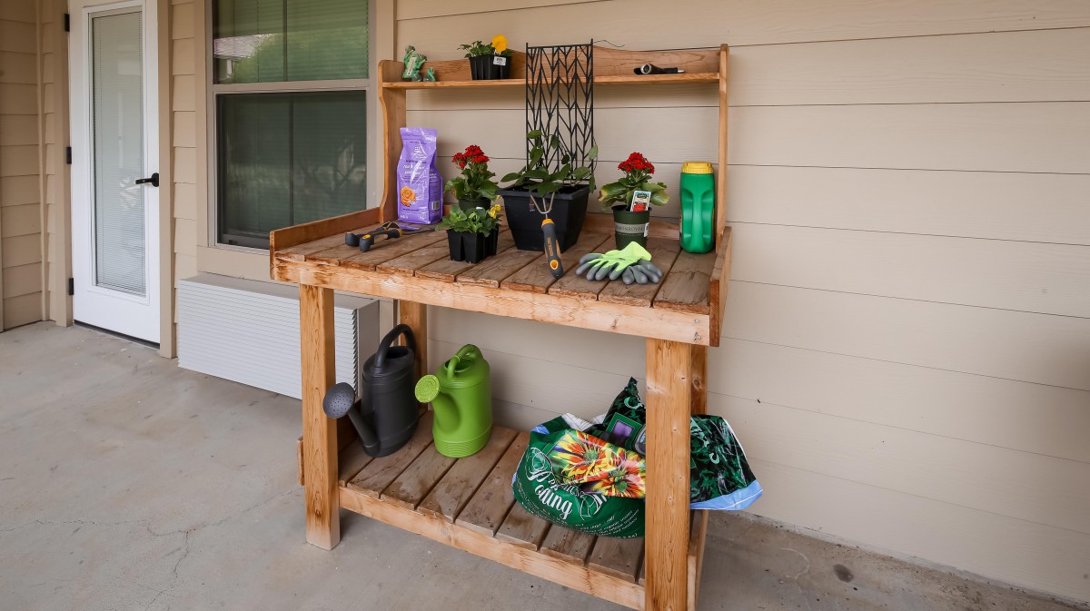 A wooden potting bench with gardening supplies and potted plants.