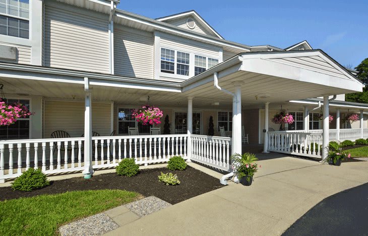 A two-story residential building with a covered porch and landscaped entrance.