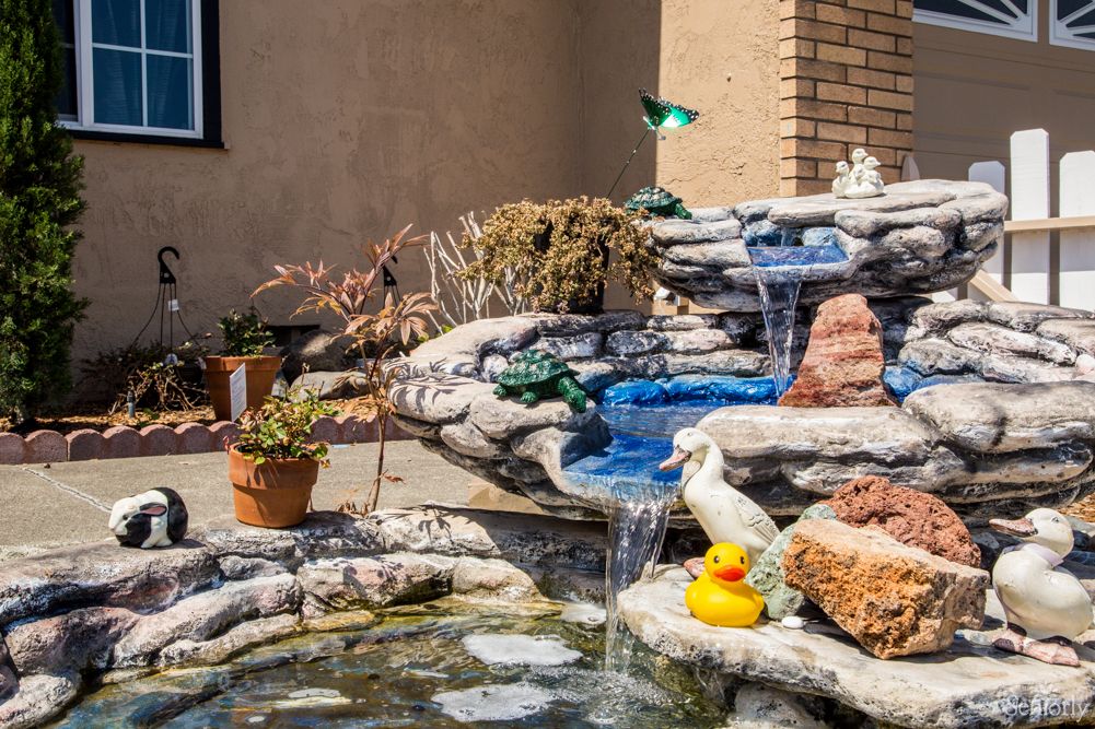 A garden fountain with cascading water, featuring a rubber duck and decorative elements.