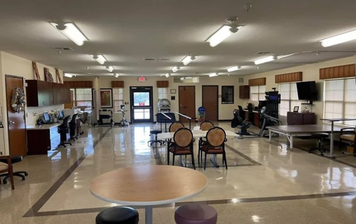 A spacious room with chairs and tables arranged neatly under fluorescent lighting.