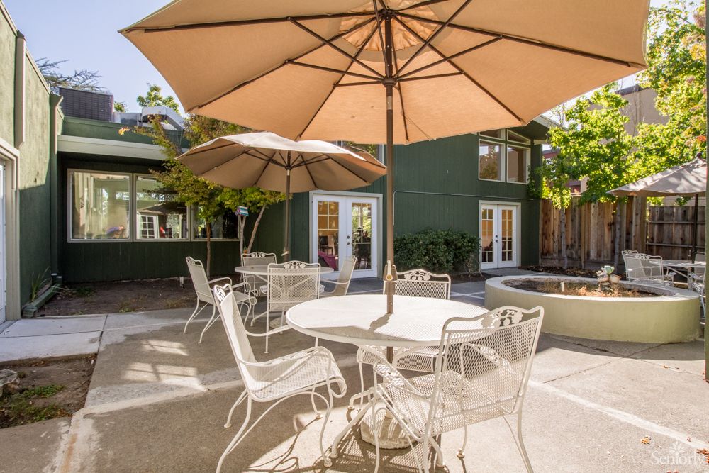 A sunny patio with outdoor seating and umbrellas in a residential garden.