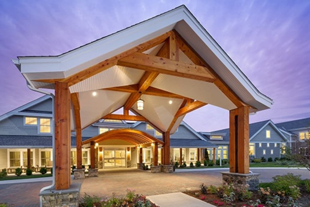 A modern building entrance with a wooden overhang and illuminated lights.