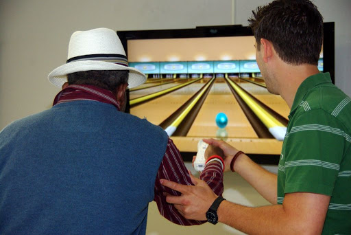 Two individuals enjoying a bowling video game, showcasing the interactive experience.
